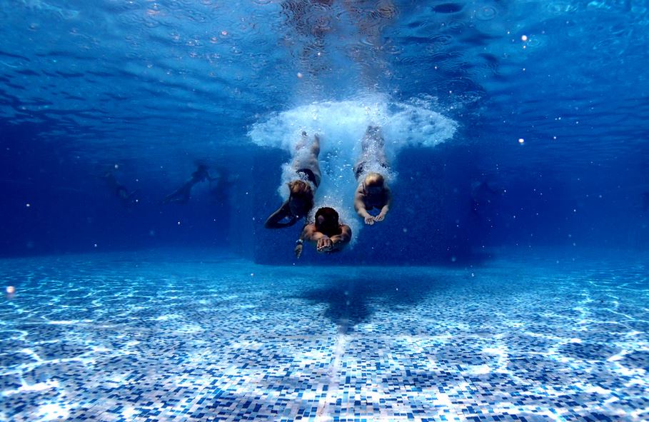 3 personnes qui plongent dans une piscine